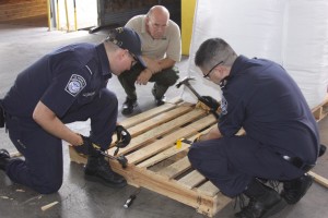 CBP agriculture specialists in Laredo, Texas, examine a wooden pallet for signs of insect infestation. [Note presence of an apparent ISPM stamp on the side of the pallet] Photo by Rick Pauza